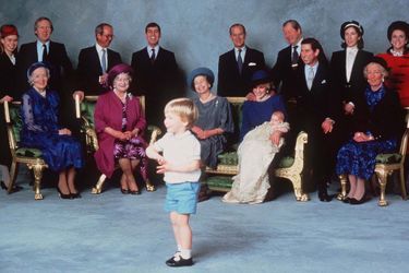 Décembre 1984 : le prince William s'amuse au baptême de son frère, le prince Harry, devant la famille et les proches de la famille royale. Lady Celia Vestey se trouve derrière le prince Charles, en chapeau noir et blanc.