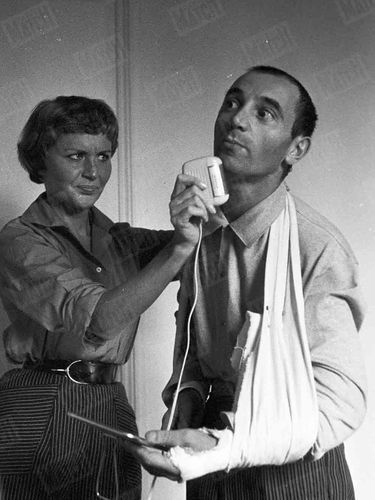 La première photo de Charles Aznavour publiée dans Match, numéro 392, daté du 13 octobre 1956. Le chanteur a les deux bras plâtrés après un accident de voiture, et son épouse Evelyne Plessis l'aide à se raser avant un concert.