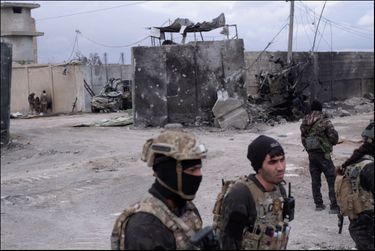 Des membres des forces antiterroristes devant l’entrée de la prison, avec les restes carbonisés d’un des deux camions utilisés par un commando suicide de Daech. À