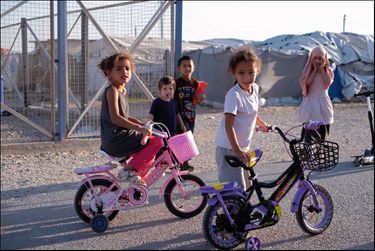 Dans le camp de Roj, trois petites filles françaises sur leurs vélos achetés sur place. Celle qui met ses mains sur son visage prend garde à ne pas être photographiée