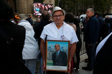 Un homme pose avec un portrait du président Chirac devant l'église Saint-Sulpice, à Paris, lundi.