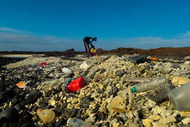 Un bénévole ramasse les déchets plastique sur les plages des Galapagos.