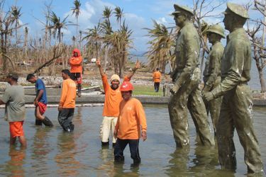 « Comme en 1944… » Plage de Palo, au sud de Tacloban, auparavant nommée Plage Imelda du temps des Marcos. Monument à la gloire du Général Mac Arthur et des Américains qui débarquèrent sur cette plage en 1944 pour libérer les Philippines de l’occupant Japonais (une des plus grandes batailles de la deuxième guerre, première fois que les Japonais utilisèrent des kamikazes). Une des statues en bronze de 3 mètres s’est affaissée durant le typhon. Des sauveteurs philippins venus de Manille y célèbrent symboliquement l’arrivée de l’aide américaine. « Nous sommes reconnaissants aux Américains de venir nous sauver pour la deuxième fois »). Ce sont les Etats-Unis qui fournissent l’essentiel de la logistique des secours.