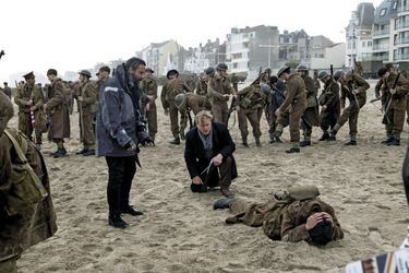 Pendant le tournage, sur la plage de Dunkerque. Le réalisateur Christopher Nolan, accroupi au centre.