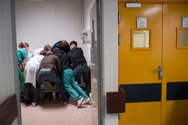 Une prime de risque de 70 centimes à 4 euros... dans le box 5, trois infirmiers (en vert), deux médecins dont un psychiatre (en blanc), un vigile et deux policiers immobilisent un patient.