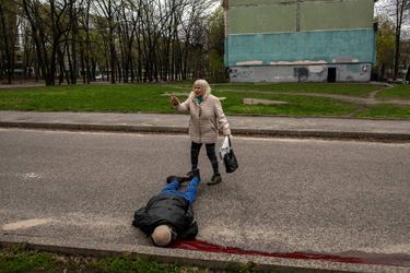 Une femme se tient près du corps d'un homme, une des victimes des frappes sur Kharkiv, le 19 avril 2022.