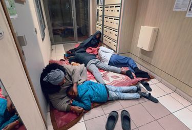 Dans le département de la Seine-Saint-Denis, une famille trouve refuge dans un hall d’immeuble après une journée d’errance, le 5 décembre 2022.