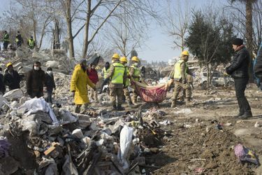 Dans une couverture, un cadavre extrait des ruines d'un bâtiment de neuf étages, à Kahramanmaras, le 11 février. Autour, les familles sont regroupées pour identifier les morts.