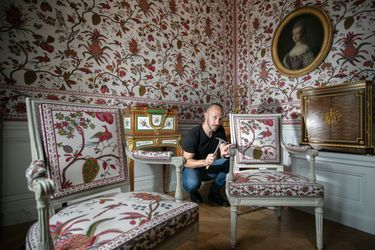 Laurent Jannin, tapissier des ateliers du château, met la dernière main aux fauteuils originaux du boudoir de la reine. Aux murs, la toile dite « au Grand Ananas », une des plus belles productions de la manufacture de Jouy.