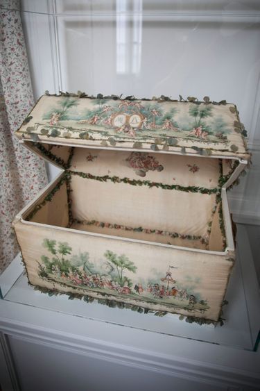 Un coffre à layette en bois et taffetas de soie peinte représentant des jeux d’enfants. Il aurait été offert par la ville de Paris en 1781, pour la naissance de Louis-Joseph, fils aîné et héritier du trône.