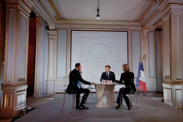 This photograph taken on March 14, 2024, shows a television screen broadcasting France's President Emmanuel Macron (C) addressing a live interview on French TV channels TF1 and France 2 with TF1's host and journalist Gilles Bouleau (L) and France Televisions' host and journalist Anne-Sophie Lapix (R), at the Elysee Presidential Palace in Paris. Emmanuel Macron said on March 14, 2024, that France would 