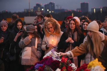 People lay flowers and light candles standing next to the Crocus City Hall, on the western edge of Moscow, Russia, Saturday, March 23, 2024. Russia's top state investigative agency says the death toll in the Moscow concert hall attack has risen to over 133. The attack Friday on Crocus City Hall, a sprawling mall and concert venue on Moscow's western edge, also left many wounded and left the building a smoldering ruin. (AP Photo/Alexander Zemlianichenko)/XAZ171/24083685526175//2403232026