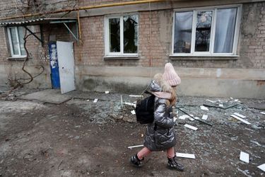 Une fillette passe devant un immeuble à Yassynouvata, près de Donetsk, qui, selon les habitants, a été endommagé par de récents bombardements, le 24 février 2022.
