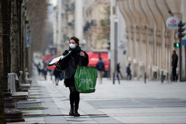 Une jeune femme portant un masque marche dans les rues de Paris.