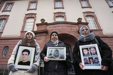 Samaa Mahmoud, Mariam Alhallak et Yasmen Almashan tiennent les portraits de leurs proches tués en Syrie, devant le tribunal de Coblence, le 13 janvier 2022.