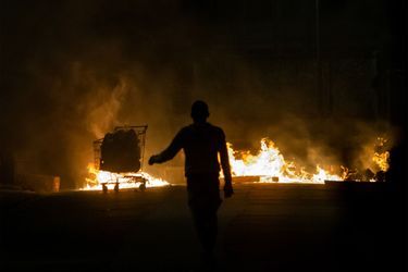 Une personne marche près d'une barricade en feu sur une route du Lamentin, en Martinique, le 1er décembre 2021, après plus d'une semaine de violentes manifestations déclenchées par les restrictions de Covid-19.