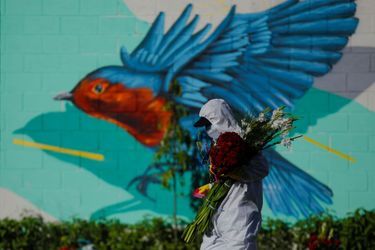 Un employé de cimetière tient des fleurs lors du jour des morts à San Salvador.