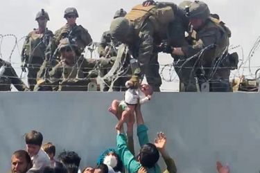 Cette photo a fait le tour du monde: un bébé est évacué par des militaires américains alors qu'une cohue s'est formée devant le mur extérieur de l'aéroport de Kaboul. 