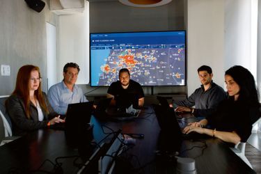 Shalev Hulio, l’un des fondateurs de NSO (au centre), avec ses collaborateurs en août 2020 devant une carte des foyers du Covid. Une de leurs applications permet de les tracer.