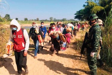 Des soldats thaïlandais accueillent les villageois qui ont fui les combats entre l’armée birmane et la rébellion karen, fin décembre.