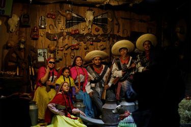 Une famille vêtue de tenues de révolutionnaires mexicains pose pour une photo dans un stand lors d'une foire de Noël à Mexico.