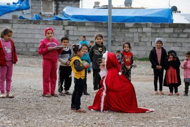 Une femme irakienne, déguisée en mère Noël, joue avec des enfants déplacés au camp de Baharka à Erbil, en Irak.