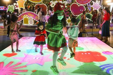 Des enfants portant des masques admirent des décorations illuminées assemblées avant la saison de Noël et du Nouvel An dans un grand magasin de Bangkok, en Thaïlande.