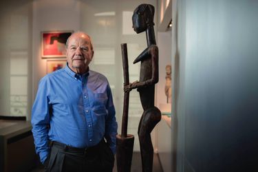Dans son bureau, Marc Ladreit de Lacharrière pose devant une sculpture dogon.