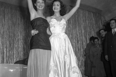 Juliette Figueras, Miss France 1949 (en robe blanche), en compagnie de sa première dauphine Colette Deréa, le soir de son élection, le 21 décembre 1948, au cabaret &quot;Le Tyrol&quot;, à Paris.