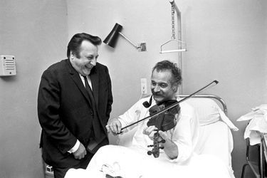 Avec son ami Raymond Devos en professeur de violon, à la clinique où il a été hospitalisé pour un calcul rénal. À Paris, le 19 mai 1967.