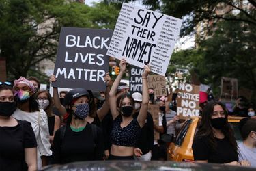 Des manifestantes portent des panneaux sur lesquels sont écrits les noms de victimes noires. 