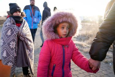 Une enfant tient la main de sa mère alors qu'elle sort du poste frontière de Medyka, en Pologne.