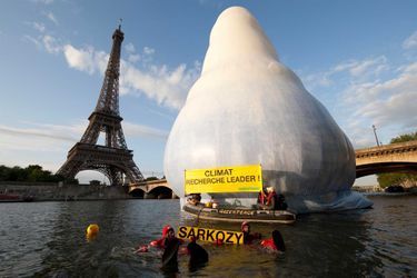 7 juillet 2009. Des militants de Greenpeace déploient des banderoles devant un iceberg grandeur nature sur la Seine et la tour Eiffel en arrière-plan pour alerter sur l'impact du changement climatique, un jour avant le début du sommet du G8.