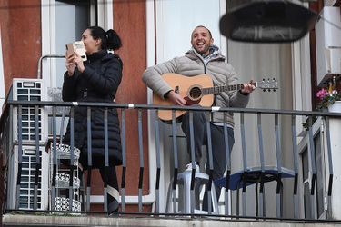 Un homme pousse la chansonnette au balcon de son appartement, à Milan, en Italie. 