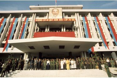 Dignitaires et soldats communistes célèbrent leur victoire, le 30 avril 1975. Sur la façade du palais de la réunification, un portrait d’Hô Chi Minh.