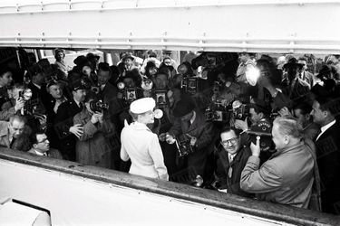 « La première conférence de presse de Grace Kelly à bord du &quot;Constitution&quot;. En tailleur tweed beige et chapeau de paille blanche, elle reçoit protégée par des policiers, l&#039;assaut de deux cents reporters et photographes. Cinq minutes après, le bateau appareillait vers Monaco et s&#039;effaçait peu à peu dans la brume.  » - Paris Match n°366, daté du 14 avril 1956..