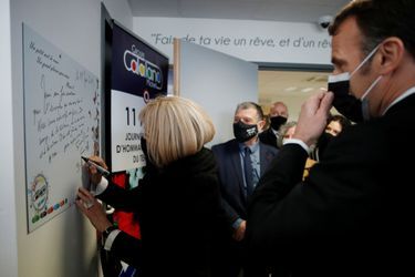 Brigitte Macron inscrit un mot sur un mur du souvenir.