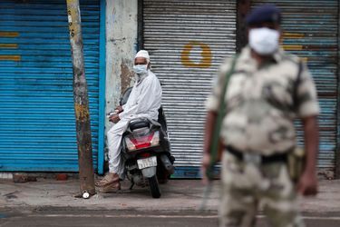 Un homme musulman porte un masque à l'entrée de Jama Masjid, une mosquée, pendant l'Aïd, près d'un soldat dans les vieux quartiers de Delhi. 