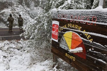 Les membres de la Garde nationale du Colorado surveillent un barrage routier menant à l'incendie de Cameron Peak alors que la neige tombe un jour après que la région a subi des records de chaleur.