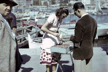 Sur le Vieux Port de Marseille, une jeune fille vend des bigorneaux dans des cornets en papier. Septembre 1950. 
