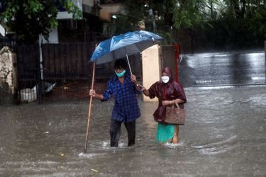 Un homme et une femme traversent une route inondée à Mumbai en Inde le 5 août 2020