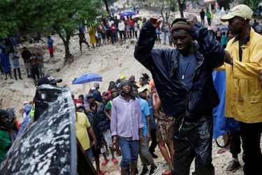 Un homme dévasté devant la corps sans vie de sa mère, tuée pendant la tempête à Port-au-Prince.