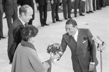 Henri Salvador offre des fleurs à Anne-Aymone Giscard d'Estaing sous le regard de Valéry Giscard d'Estaing avant le départ du président et de sa femme pour les Antilles, Orly le 12 décembre 1974, France. 