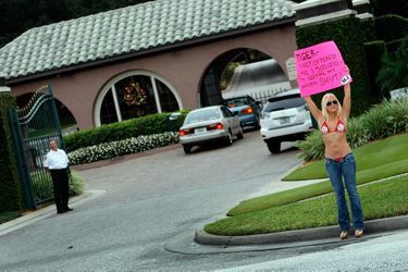 Une &quot;supportrice&quot; de Tiger Woods devant sa résidence de Floride, tenant une pancarte : &quot;Tiger, on m&#039;a offert 500 000 $, mais je vais la fermer !&quot; 