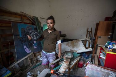 Hasan Al Armali pose dans sa chambre détruite. Il tient une horloge qui s'est arrêtée au moment des déflagrations. 