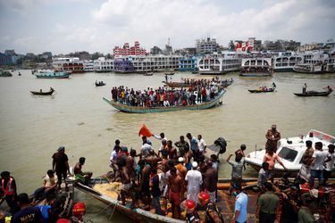 Des badauds regardent le lieu du naufrage depuis une embarcation sur le fleuve de Buriganga à Dacca. 