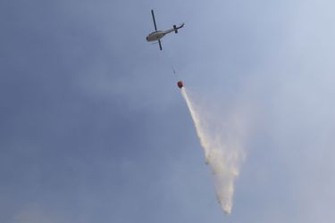 A Sonoma, samedi, un hélicoptère bombardier d'eau largue sa cargaison près des maisons menacées par les flammes.