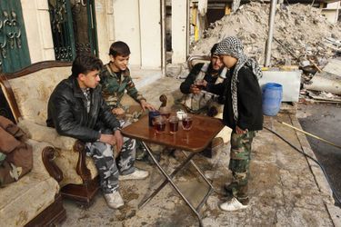 Pause détente. Hasan, un combattant de 11 ans,set le thé aux adultes à Alep. 