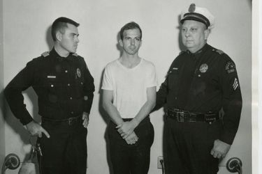 Lee Harvey Oswald entre deux policiers, peu après son arrestation.