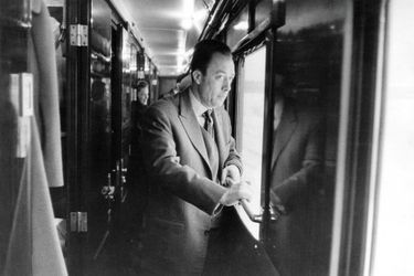 Albert Camus, prix Nobel de littérature en 1957 pour l&#039;ensemble de son oeuvre, part en Suède en train pour recevoir le prix : attitude de l&#039;écrivain debout dans un couloir, regardant par une vitre.